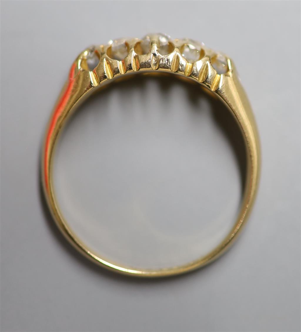 An early 20th century 18ct gold and graduated five stone diamond set half hoop ring, size P, gross 4 grams.